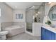 Modern bathroom featuring a soaking tub, glass-enclosed shower, and blue vanity at 3196 Mateuse St, Logandale, NV 89021