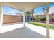 A covered patio in a backyard with brick wall, lush lawn, and mature shade trees at 3505 Tuscany Village Dr, Las Vegas, NV 89129