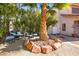 Private backyard seating area with a mature palm tree, desert landscaping, and ambient shade at 3620 Bahama Bay Ct, Las Vegas, NV 89147