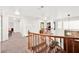 Sunlit upstairs loft featuring wood railing, neutral carpet, and front door view at 3620 Bahama Bay Ct, Las Vegas, NV 89147