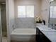 Bathroom featuring a bathtub with marble-style tiling and a vanity with a sink and faucet at 425 Donner Pass Dr, Henderson, NV 89014