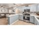 Modern kitchen featuring stainless steel appliances, a quartz countertop bar, and soft blue cabinetry at 4786 Valleyside Ave, Las Vegas, NV 89115