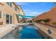 Inviting swimming pool with a waterfall feature and blue sunshade, creating a private backyard oasis at 5971 Sonoma Station Ave, Las Vegas, NV 89139