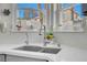 A view of the modern kitchen sink, window with decorations, and quartz countertop at 6109 Flaming Arrow Rd, North Las Vegas, NV 89031