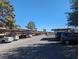 View of the apartment complex parking area with covered parking spaces, trees, and clear skies at 615 S Royal Crest Cir # 15, Las Vegas, NV 89169