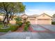 Well-maintained home featuring a tile roof, arched entryway, two-car garage, and landscaped front yard at 692 Quilt Pl, Henderson, NV 89052