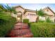 Charming home entrance with brick steps, manicured hedges, and an inviting arched gate to the courtyard at 692 Quilt Pl, Henderson, NV 89052