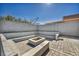 Sunlit backyard patio featuring a fire pit, brick paving, and modern concrete bench seating around the perimeter at 7308 Alpine Ridge St, Las Vegas, NV 89131