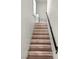 A stairway with wood-look steps and a black handrail provides a modern and stylish transition between floors at 8301 Boseck Dr # 215, Las Vegas, NV 89145