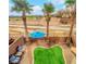 Aerial shot showcases a cozy backyard with a small lawn, umbrella, desert landscaping, and mature palm trees at 8349 Spruce Bay Ave, Las Vegas, NV 89178