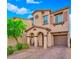 Charming two-story home with a covered entry, arched columns, tan stucco, and a lush landscaped yard and brick paver driveway at 8349 Spruce Bay Ave, Las Vegas, NV 89178