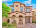 Charming two-story home with a covered entry, arched columns, tan stucco, and a lush landscaped yard and brick paver driveway at 8349 Spruce Bay Ave, Las Vegas, NV 89178