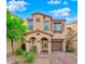 Charming two-story home with a covered entry, arched columns, tan stucco, and a lush landscaped yard and brick paver driveway at 8349 Spruce Bay Ave, Las Vegas, NV 89178