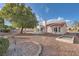 Wide view of the backyard shows gravel landscaping, mature trees and part of home exterior at 9421 Gold Mountain Dr, Las Vegas, NV 89134