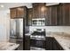 Modern kitchen featuring stainless steel appliances, granite countertops, and dark wood cabinets at 965 Nevada State Dr # 39201, Henderson, NV 89002