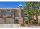 Inviting townhouse featuring a private garage and landscaped front with mature shade trees at 9655 Idle Spurs Dr, Las Vegas, NV 89123