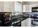 Well-lit kitchen showcasing modern appliances, black countertops, and mosaic backsplash at 10320 Bent Brook Pl, Las Vegas, NV 89134