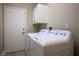 Bright laundry room featuring a white washer and dryer, storage cabinets, and a side door at 10320 Bent Brook Pl, Las Vegas, NV 89134