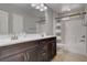 Bathroom featuring double sinks, a large mirror, and a shower-tub combination with stylish curtain at 10564 Tranquil Glade Ln, Las Vegas, NV 89135