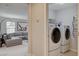 Laundry room with modern washer and dryer units, shelving, and adjacent living area at 10564 Tranquil Glade Ln, Las Vegas, NV 89135