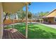 Lush backyard with artificial grass, a covered patio, mature trees, and a deck for enjoying the outdoors at 2213 Midvale Ter, Henderson, NV 89074