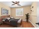 Staged bedroom featuring wood floors, ceiling fan, plantation shutters, and warm paint at 2213 Midvale Ter, Henderson, NV 89074