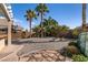 Wide angle shot of a spacious backyard with desert scape, trees, brick wall and a covered patio at 2713 Tanagrine Dr, North Las Vegas, NV 89084