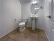 Modern half-bathroom with pedestal sink, white toilet, neutral tile flooring, and vanity mirror at 2756 Blairgowrie Dr, Henderson, NV 89044