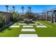 A modern backyard with artificial grass, a stone fire pit, and a gazebo for relaxing at 59 Strada Loreto, Henderson, NV 89011