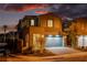 Elegant two-story home with a warm glow, showcasing a paved driveway and well-lit front yard at 59 Strada Loreto, Henderson, NV 89011