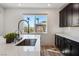 Modern kitchen island with black cabinets, quartz countertops, and stainless sink fixtures at 59 Strada Loreto, Henderson, NV 89011