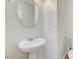 A powder room featuring pedestal sink, mirror and toilet with neutral colored walls at 6190 Tillman Crest Ave, Las Vegas, NV 89139