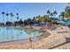 Sandy beach at community lake featuring beach umbrellas and towering palm trees at 7632 Desert Largo Ave, Las Vegas, NV 89128