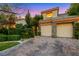 Spacious three-car garage with stone accents and a driveway of beautiful pavers, surrounded by lush landscaping at 801 Sir James Bridge Way, Las Vegas, NV 89145