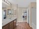 Well-lit bathroom with wood-look flooring, dual sink vanity, and an open door leading to a bedroom at 8112 Mustang Hill Ct, Las Vegas, NV 89131