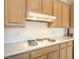Close up of stove top with wooden cabinets and white backsplash at 1 Ibis Ct, Henderson, NV 89052