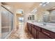 Bathroom with double sinks, granite counters, and a separate glass shower at 10746 Lightning Sky St, Las Vegas, NV 89179