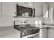 Close-up of stainless steel gas range and microwave with white cabinets and granite countertop at 11103 African Sunset St, Henderson, NV 89052