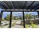 View through a pergola highlighting the manicured lawns and modern home designs of the neighborhood at 11703 Emerald Lake Ave, Las Vegas, NV 89138