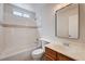 Bright bathroom featuring white tile, a shower-tub combo, and a wood vanity with a framed mirror at 1813 Pluto Dr, Las Vegas, NV 89108