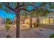 Beautiful backyard landscaping with rocks, plants, a covered patio, and mature trees at 2475 Hamonah Dr, Henderson, NV 89044