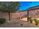 Well-maintained backyard features desert landscaping and a cozy, covered patio area with decorative lighting at 2475 Hamonah Dr, Henderson, NV 89044