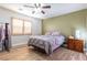 Bedroom featuring wood floors, ceiling fan, and large window with privacy shutters at 2681 Benton Cove St, Laughlin, NV 89029
