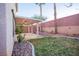 Beautiful backyard with a covered patio, green grass, palm trees, and desert landscaping with decorative rocks at 3725 Shanagolden St, Las Vegas, NV 89129
