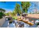 Backyard with built-in seating, a cozy brick fire pit, and mature landscaping for outdoor enjoyment at 4880 Hayride St, Las Vegas, NV 89149