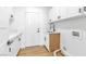 Bright laundry room with white cabinetry, stainless steel sink, and stylish wood-look flooring at 4880 Hayride St, Las Vegas, NV 89149