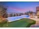 Aerial view of the serene backyard featuring a modern pool, putting green, and privacy landscaping against a twilight sky at 5184 Steel Hammer Dr, Las Vegas, NV 89135