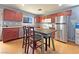 Well-lit kitchen with stainless steel appliances, wood cabinets, dining table and wood-look flooring at 5288 Emelita St, Las Vegas, NV 89122