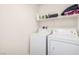 Functional laundry room with a full size washer and dryer and upper shelving at 617 Abrazar Ave, North Las Vegas, NV 89081