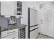 White cabinetry with beverage fridge, stainless steel refrigerator, and black marble counters at 6925 Emerald Springs Ln, Las Vegas, NV 89113